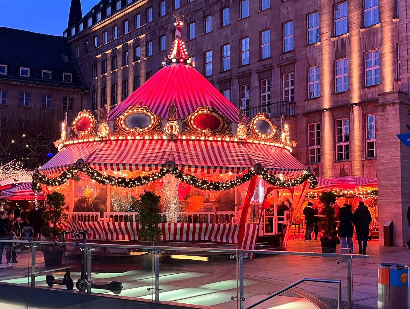 Das Bierkarussell am Abend vor dem Bochumer Rathaus, mit rot-weiß gestreiftem Dach und Lichterketten